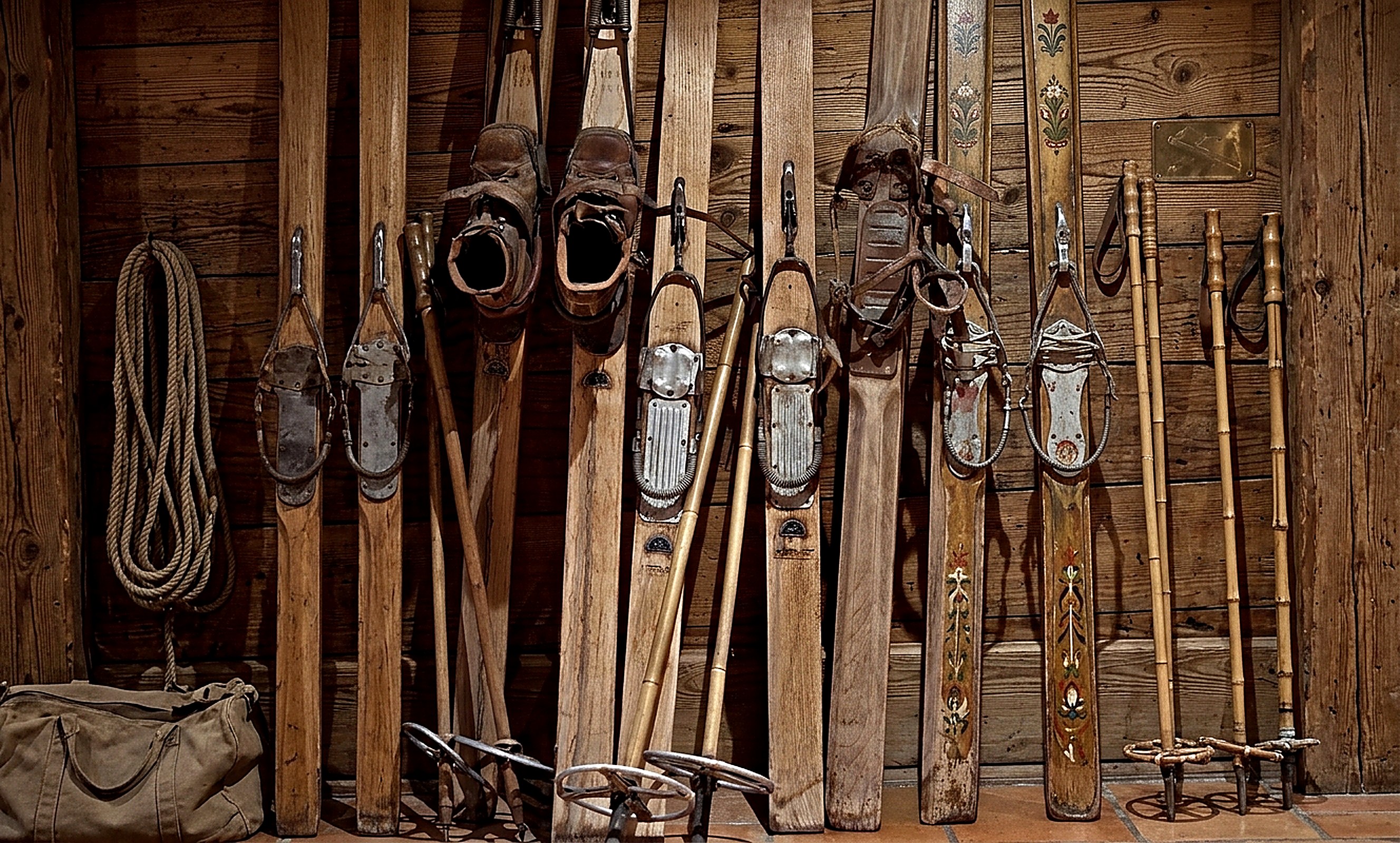 Tungsten Lodge, vintage ski memorabilia: hand-carved wooden skis, aged leather boots, bamboo poles, coiled rope and canvas duffel arranged against reclaimed timber